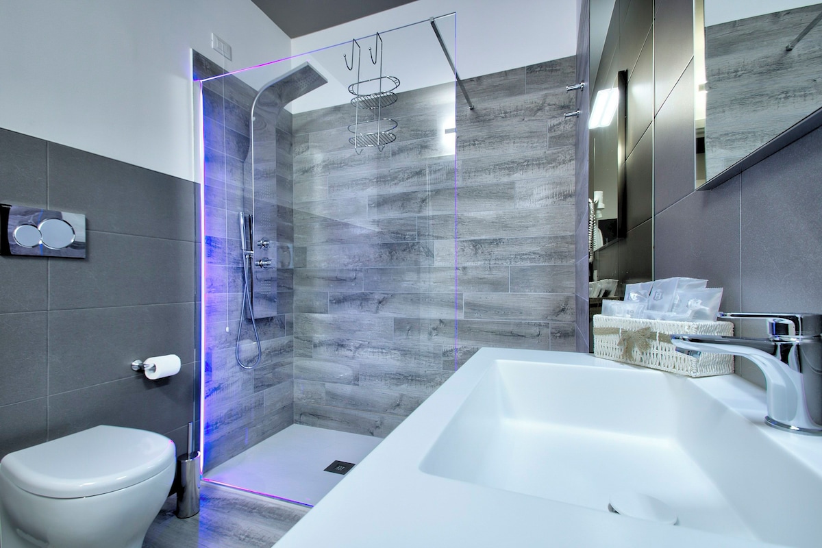 A modern bathroom with a glass-enclosed shower, a white sink, and a toilet.