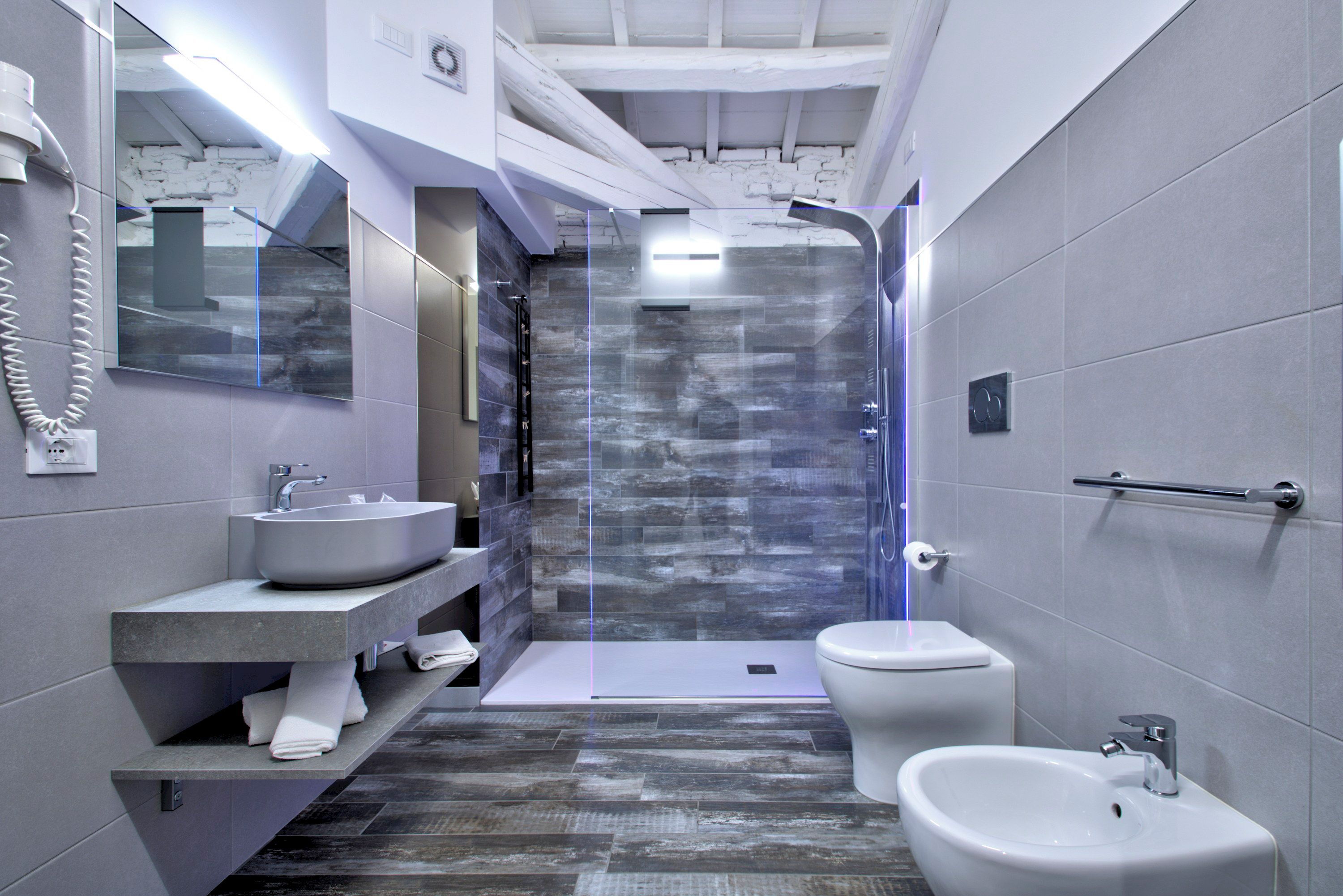 Un baño moderno con lavamanos integrado, un bidé y una cabina de ducha.