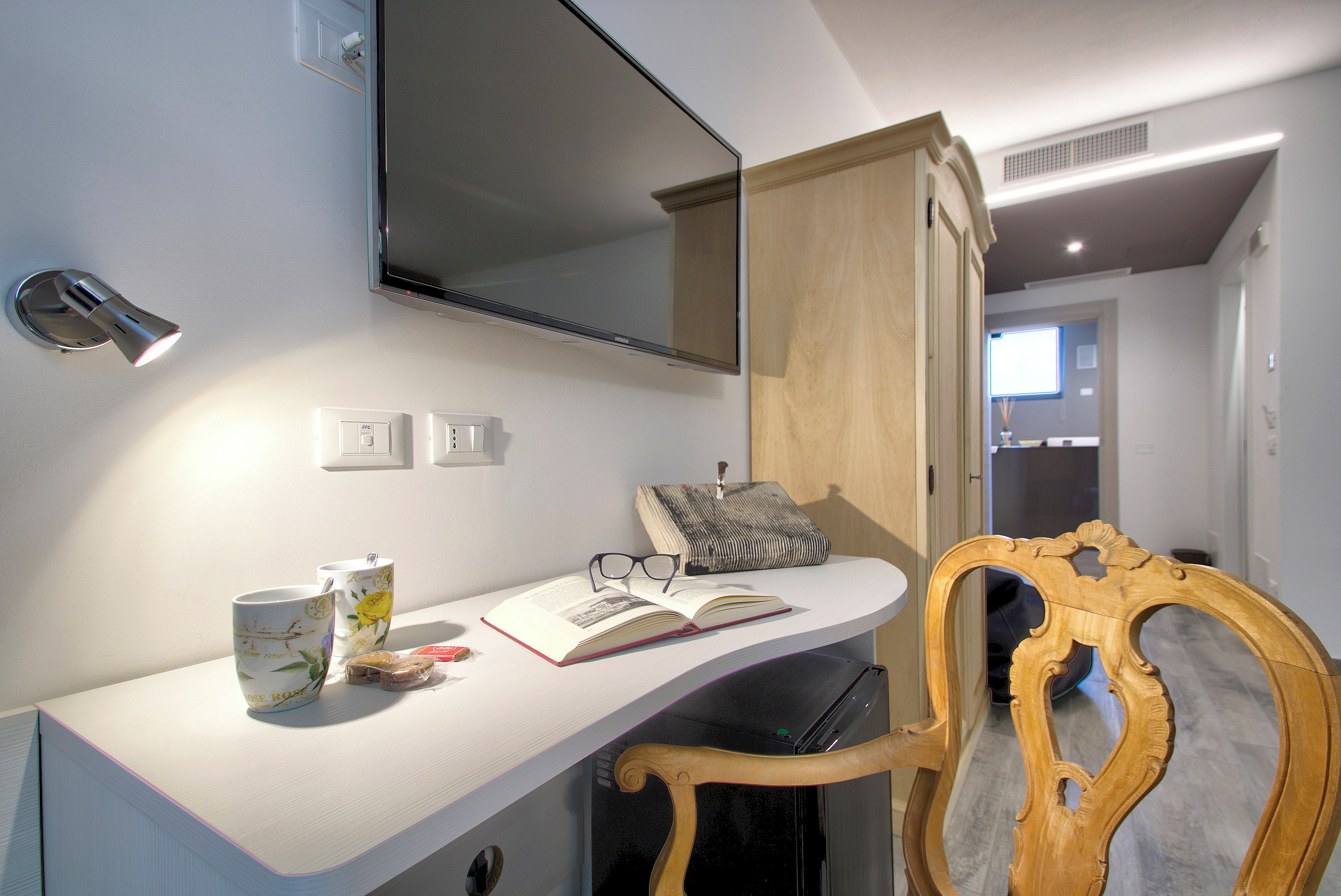 Ein modernes Badezimmer mit einem weißen Waschtisch, einem Spiegel und einem Holzkabinet.