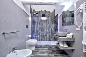 Un baño moderno con ducha, inodoro, bidé y lavamanos.