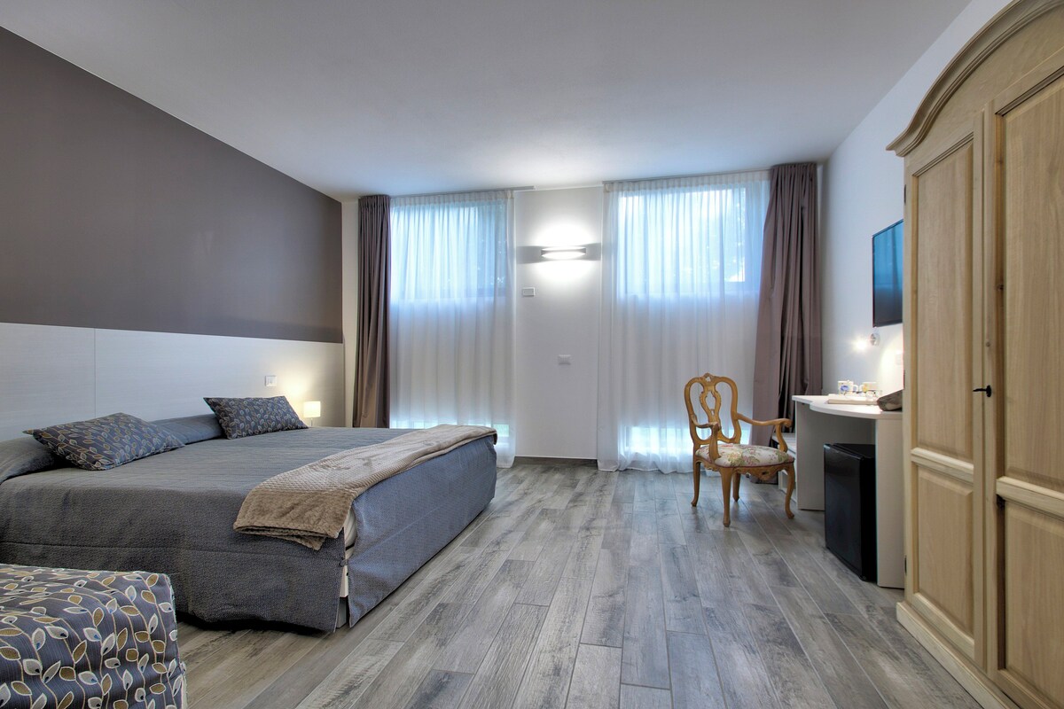 Un dormitorio con cama, una silla, un escritorio y un armario.