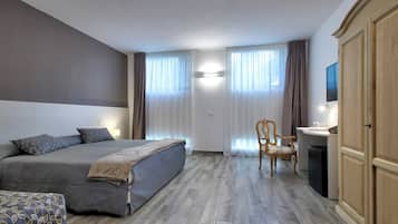 A bedroom with a bed, a chair, a desk, and a wardrobe.