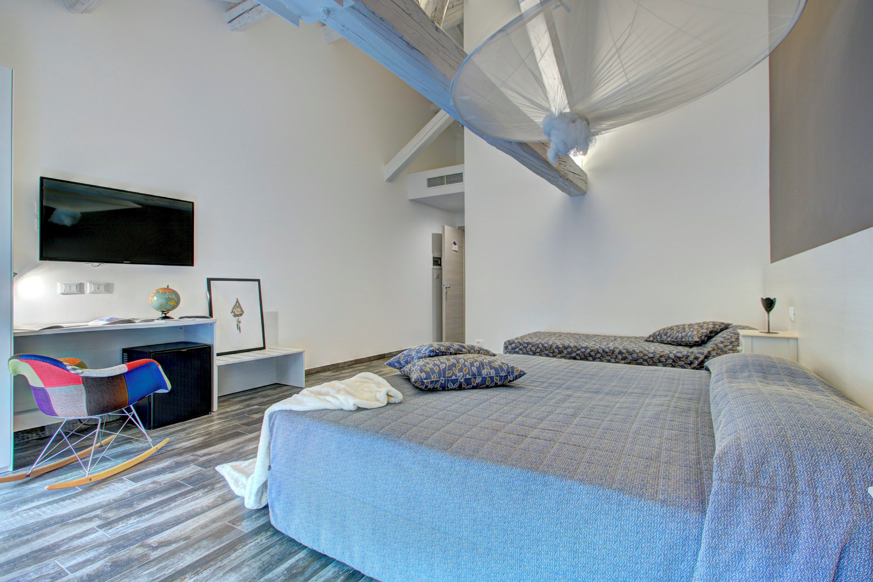 Une chambre à coucher avec un grand lit, un bureau avec une chaise, une télévision et un lit à baldaquin.