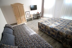 Una habitación de hotel con una cama grande, un escritorio, un televisor y un armario.