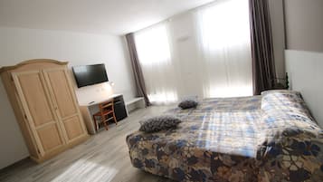 Un dormitorio con cama, escritorio, televisor y armario.