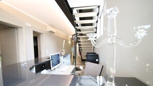 A modern office space with a glass desk, a computer, and a decorative glass object. - Resilienza (Mira)