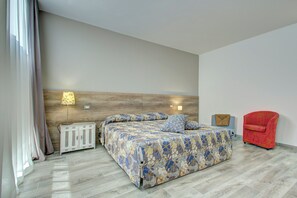 Un dormitorio con cama, mesita de noche, lámpara, silla y cabecero de madera.