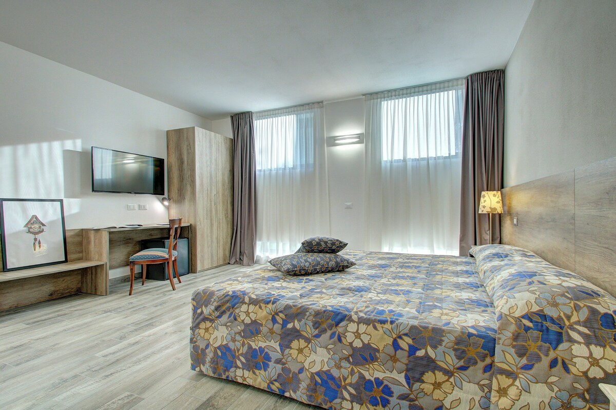 Una habitación de hotel moderna con una cama grande, un escritorio y una silla.