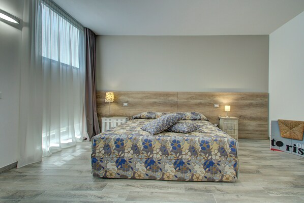 Un dormitorio con una cama grande, cabecera de madera, una mesita de noche y una lámpara de pared.
