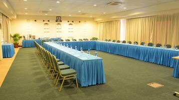 A conference room with long tables and chairs, equipped with water bottles and nameplates.