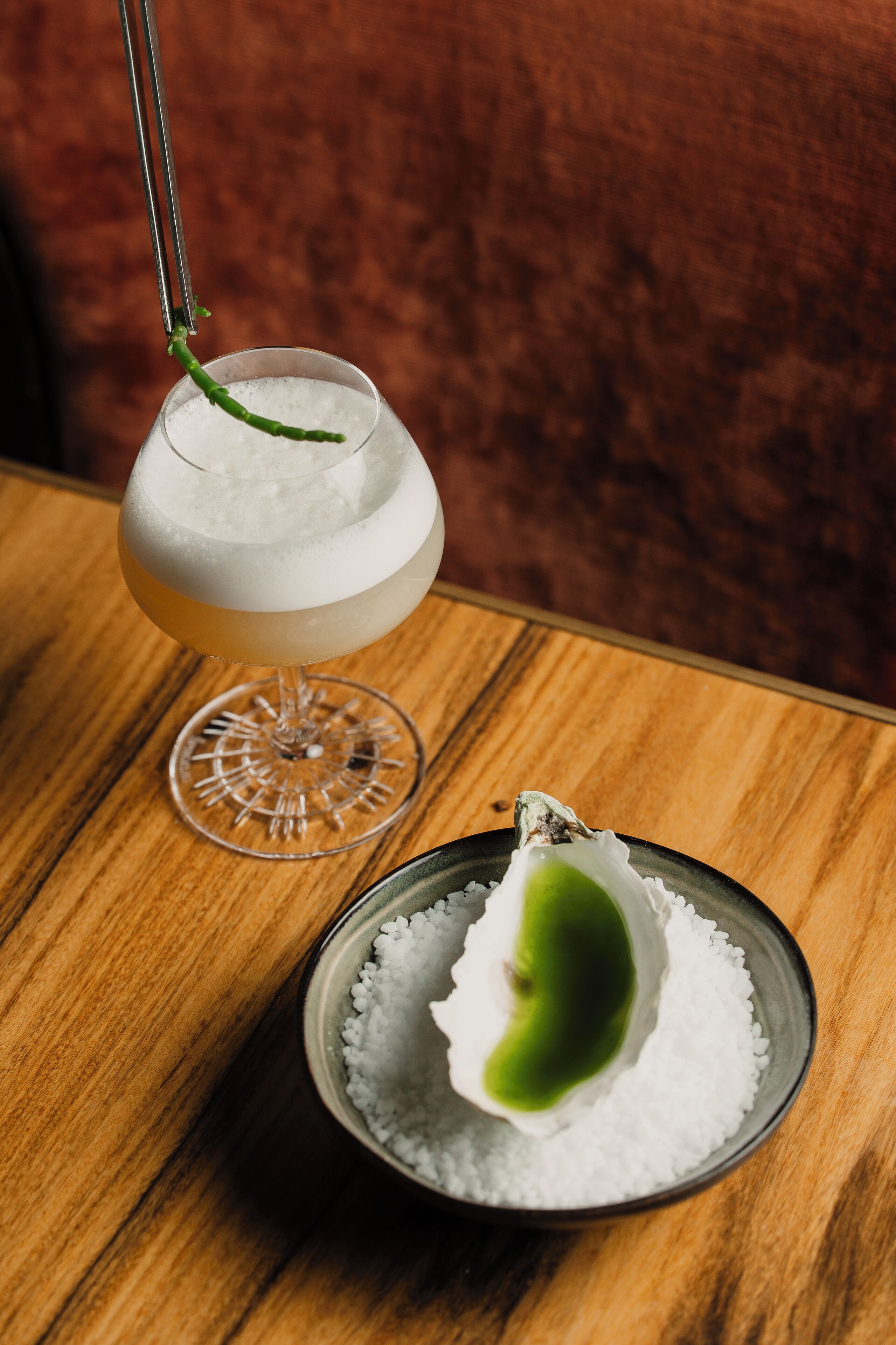 Et cocktailglas med grønt pynt på et træbord.