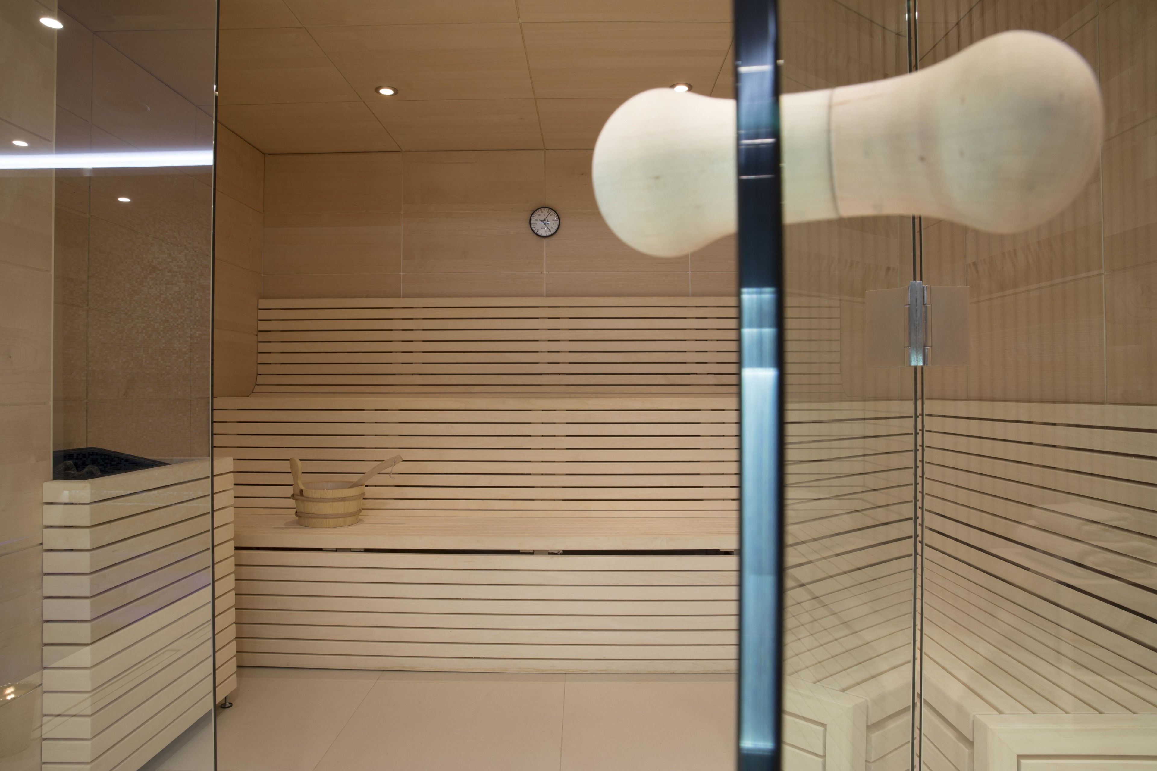 A modern bathroom with a wooden slat wall, a visible clock, and a large, white, abstract sculpture.