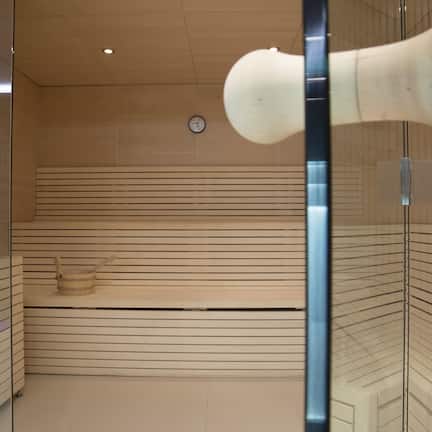 A modern bathroom with a wooden slat wall, a visible clock, and a large, white, abstract sculpture.