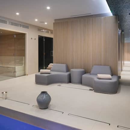 A modern lobby with a seating area, a reception desk, and a large mirror.
