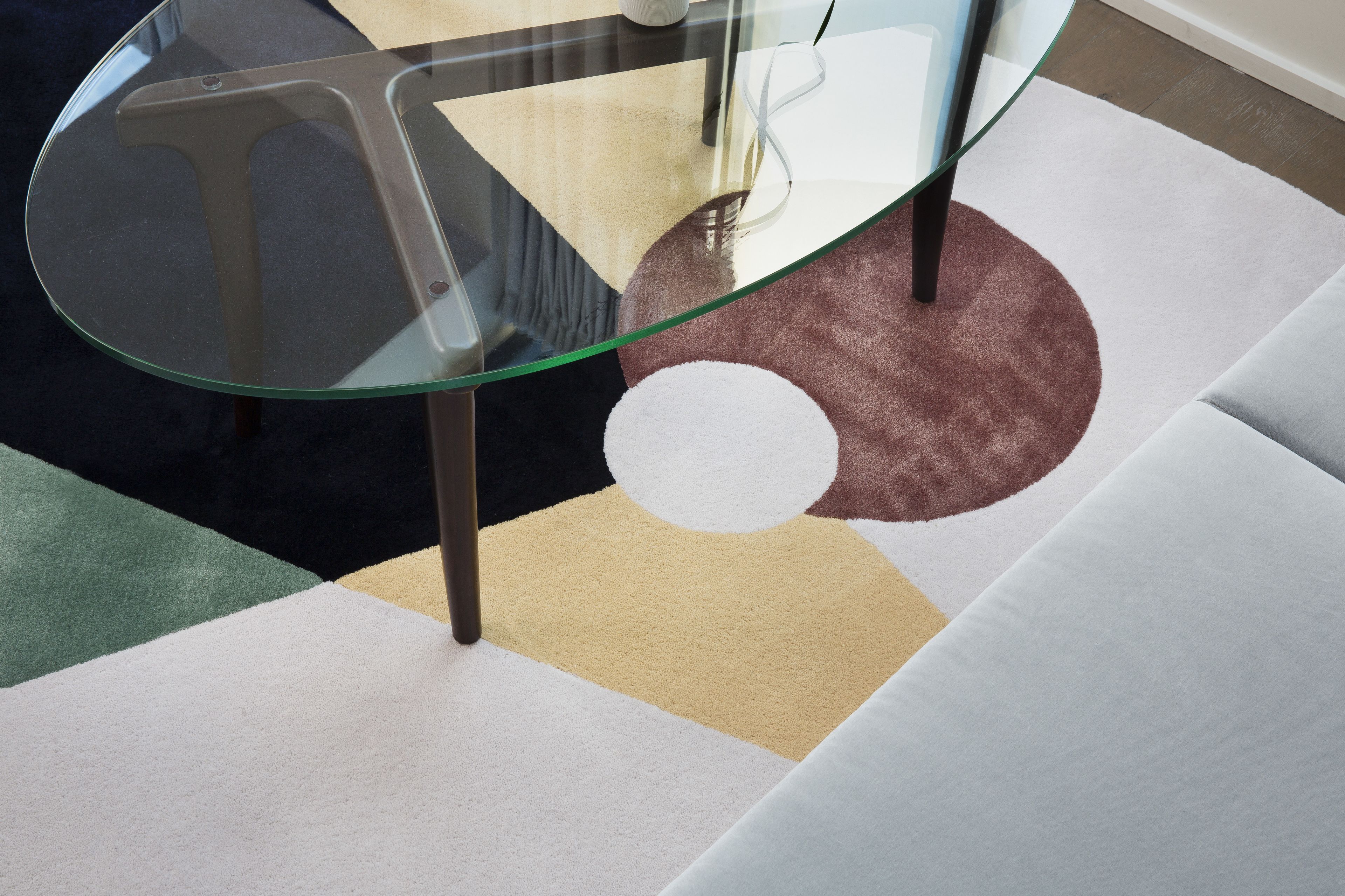 Una habitación moderna con una mesa de vidrio, una alfombra estampada y un sofá.