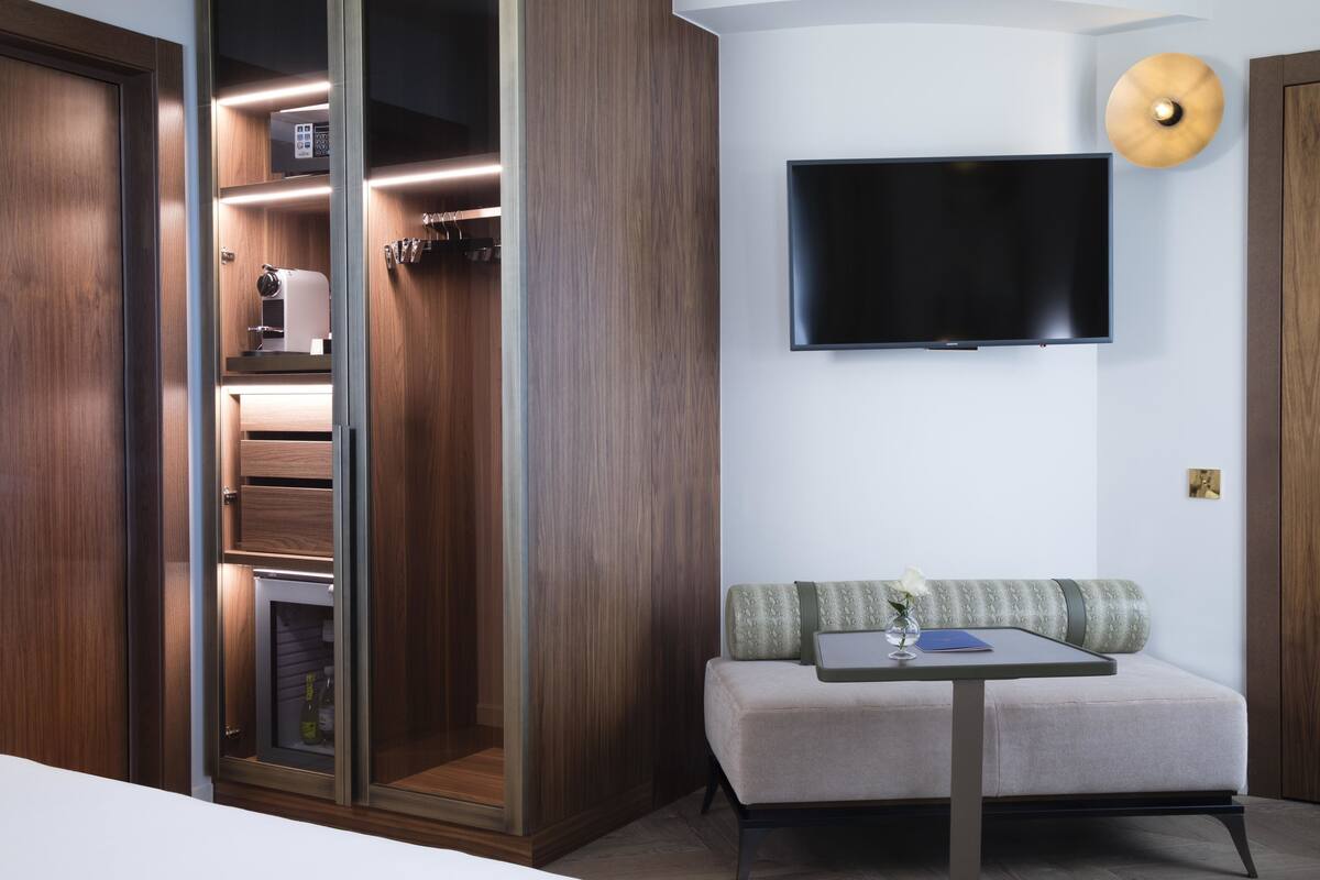 A modern room with a built-in wardrobe, a flat-screen TV, a sofa, and a small table.
