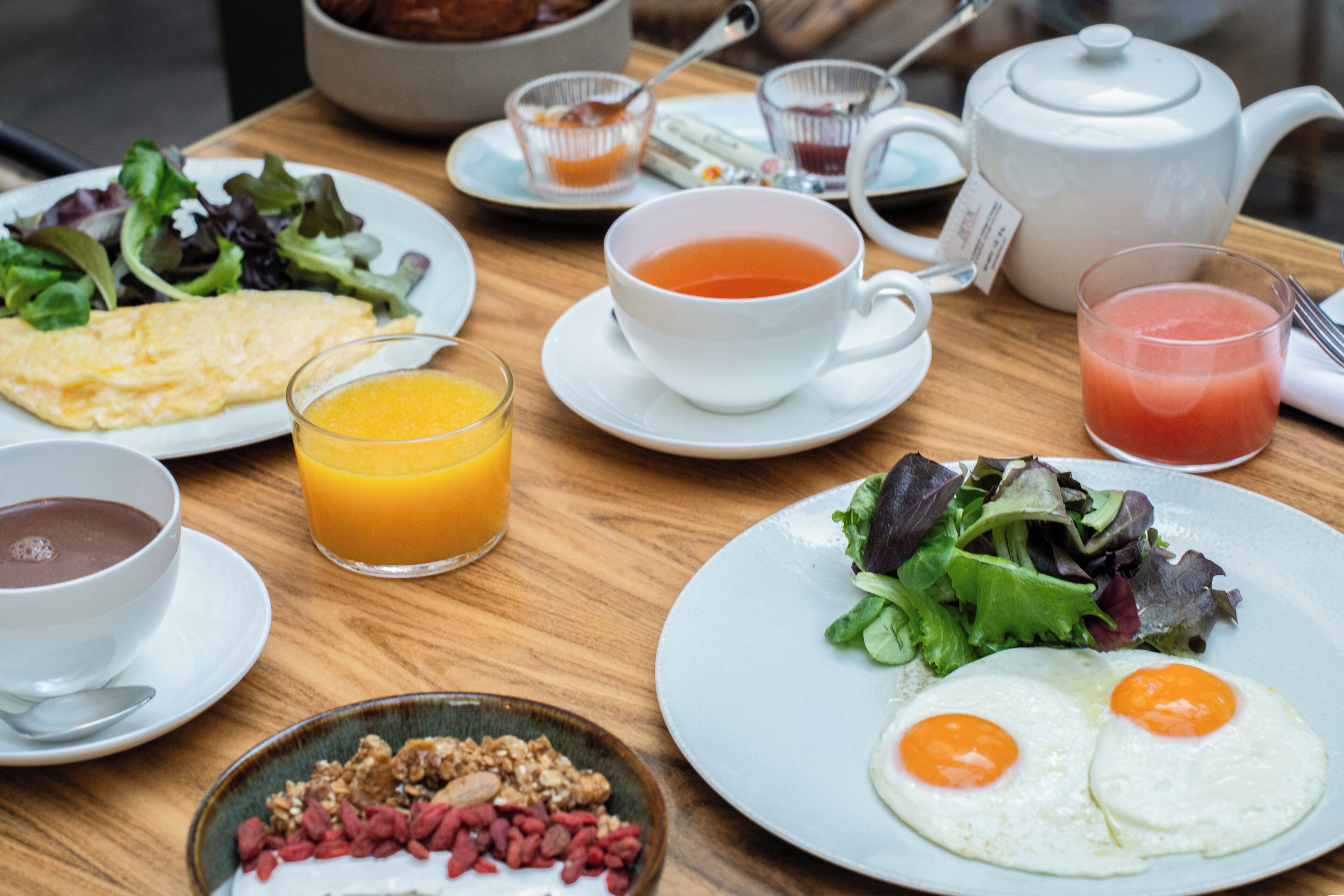 A breakfast table with various dishes including eggs, toast, and a bowl of soup.