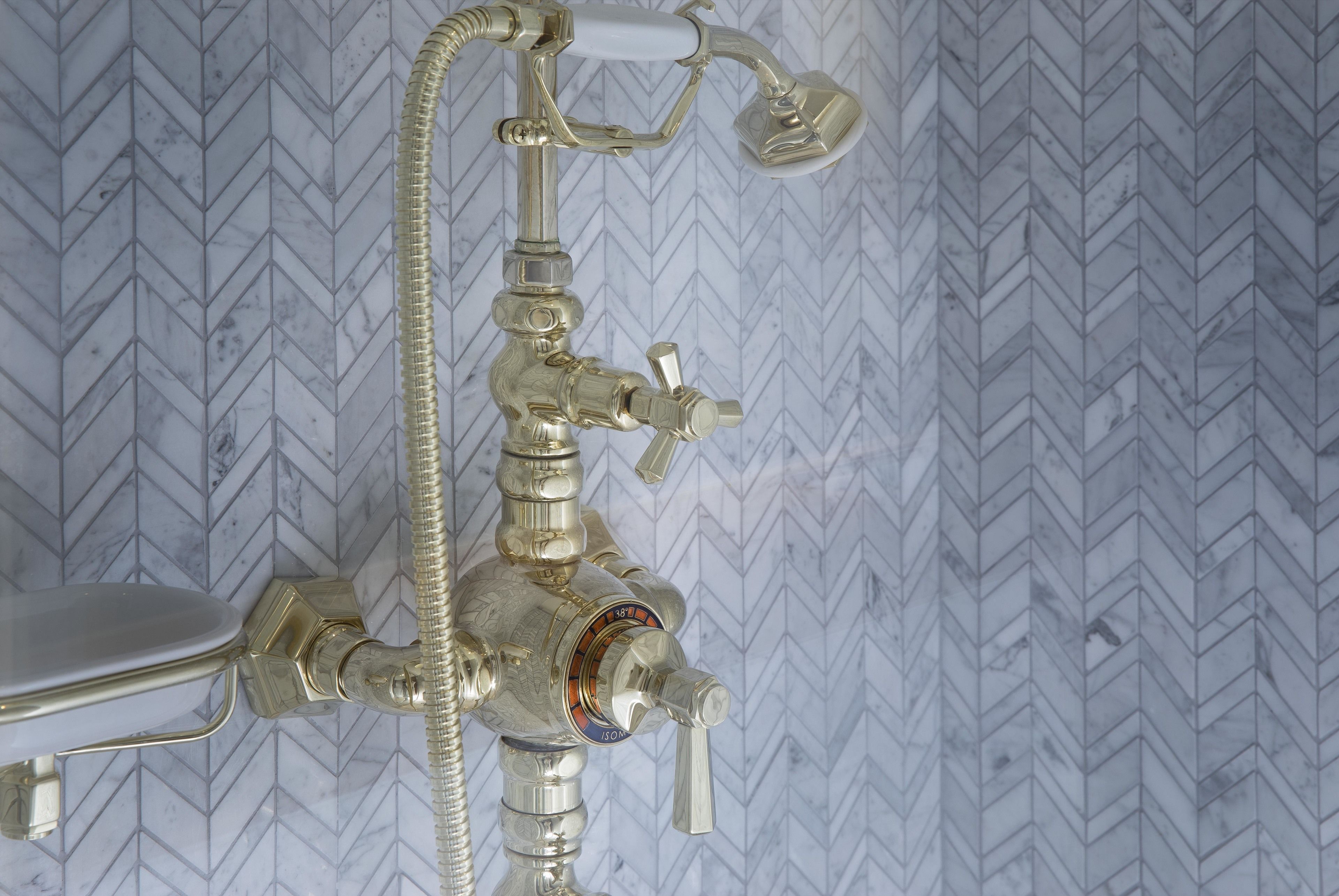 A bathroom with a modern shower system, including a handheld showerhead and a wall-mounted control panel.