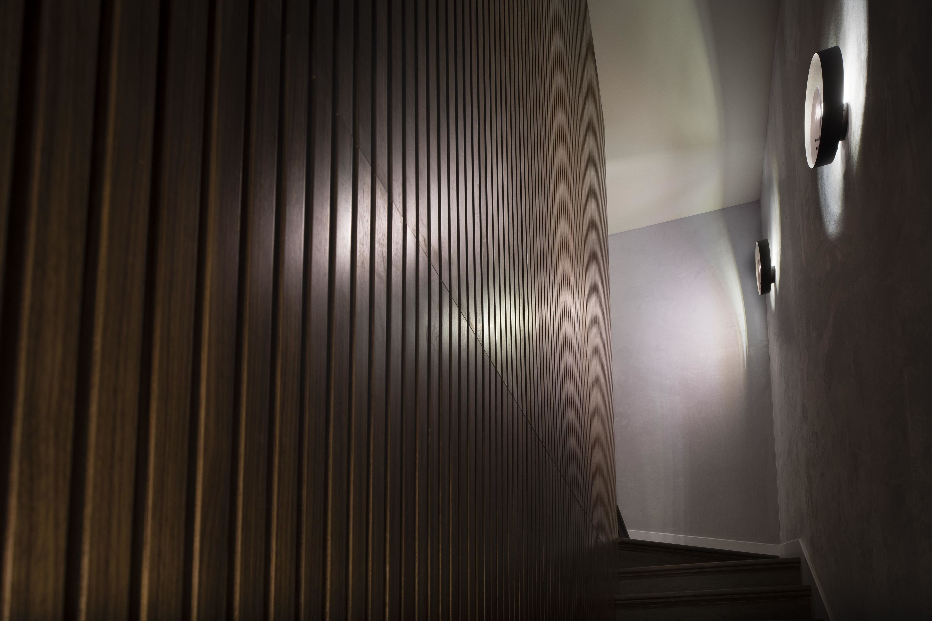 A corridor with vertical wooden slats and a light source on the right.