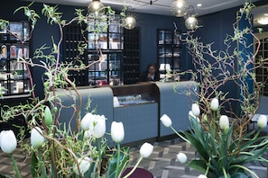 A reception area with a counter, shelves with items, and a person behind the counter.