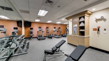 A gym with exercise equipment, a reception desk, and a mirror wall.