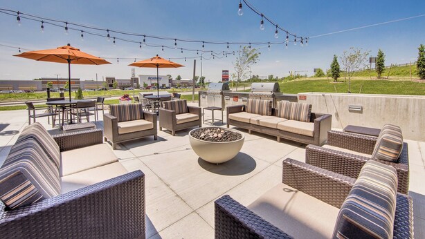 An outdoor patio area with wicker furniture, a large planter, and string lights. - TownePlace Suites by Marriott Kansas City Liberty (Liberty)
