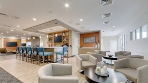 A modern hotel lobby with a bar area, seating, and a television. - TownePlace Suites by Marriott Kansas City Liberty (Liberty)