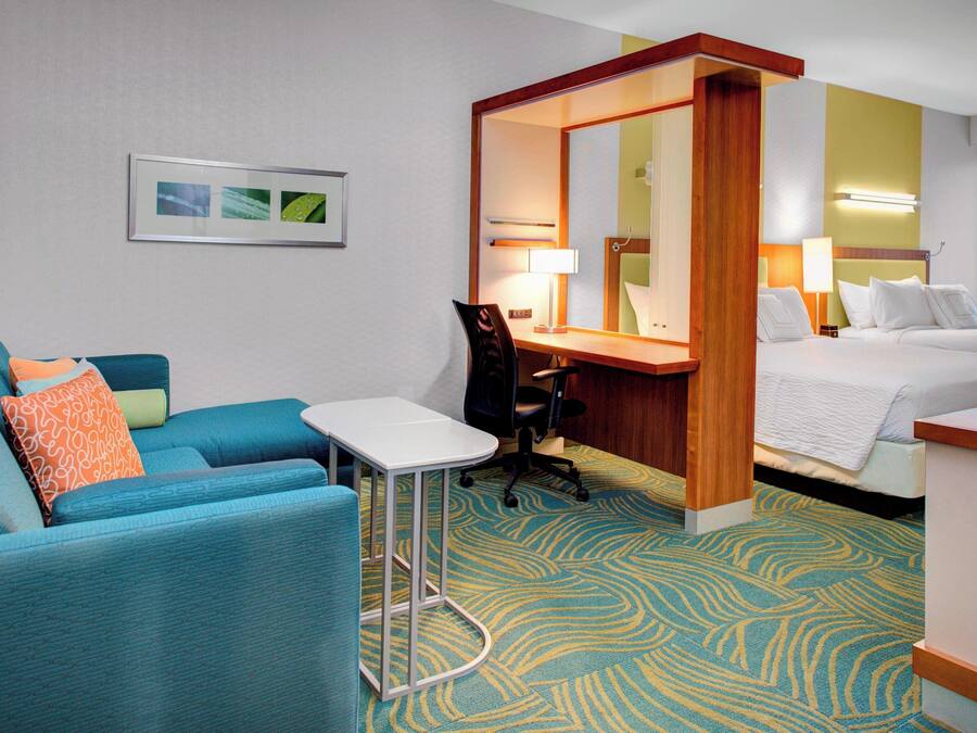 Une chambre d’hôtel avec un canapé bleu, un bureau, une chaise, un lit et un téléviseur.