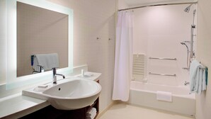 A modern bathroom with a large sink, two mirrors, a bathtub, and a shower.