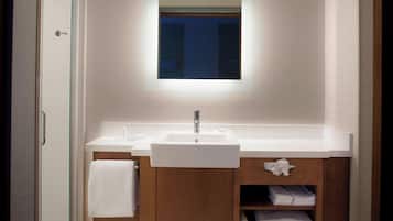 Un baño moderno con lavamanos blanco, un espejo y muebles de madera.