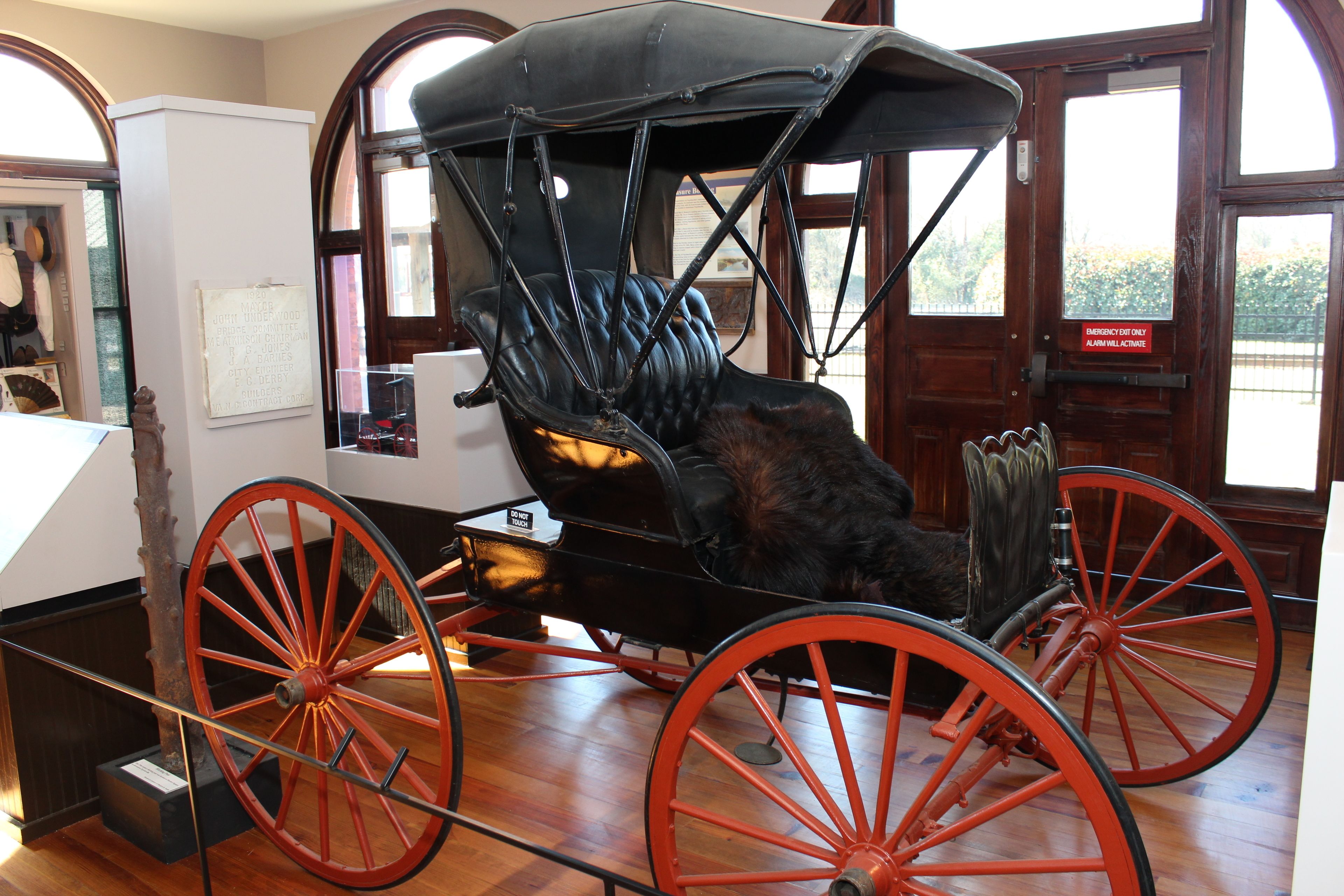 A black carriage with red wheels, a black seat, and a black canopy.