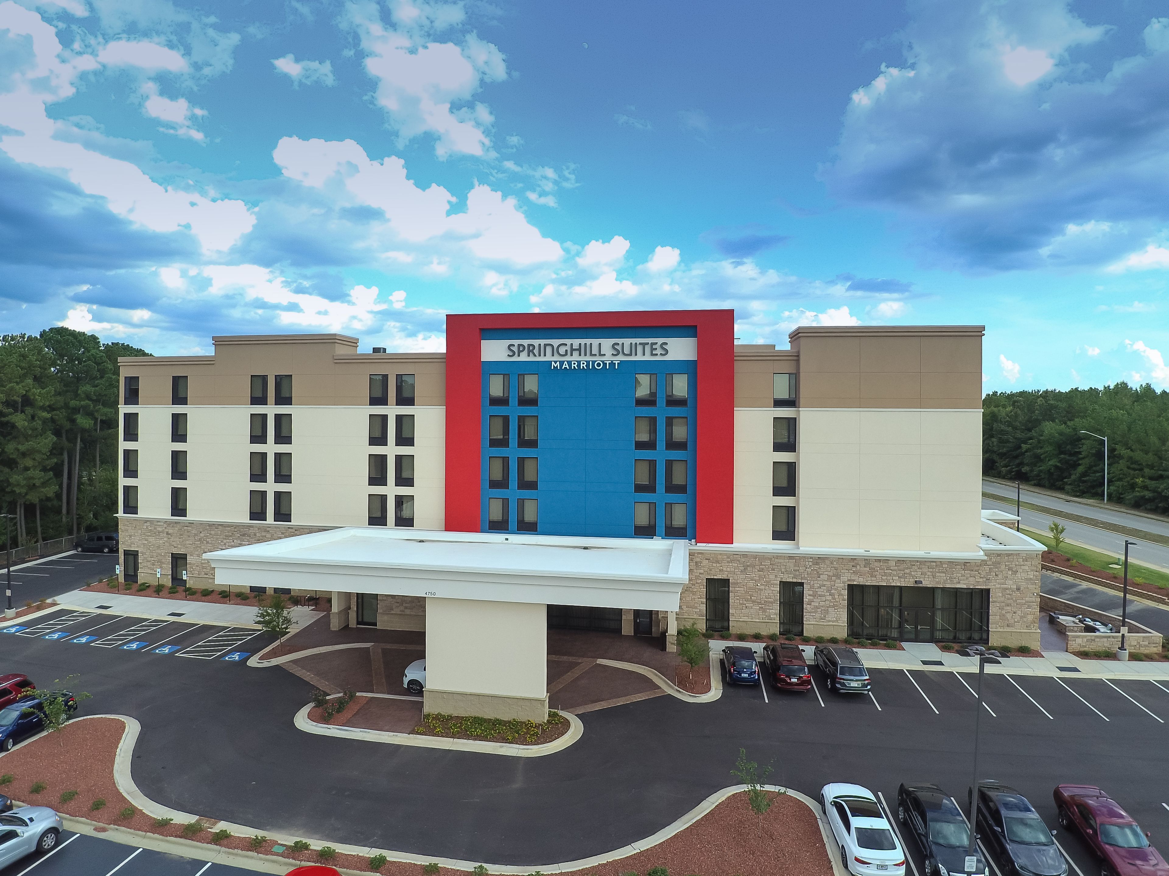 A hotel with a prominent blue and red entrance, multiple parking spaces, and a clear view of the surrounding area.