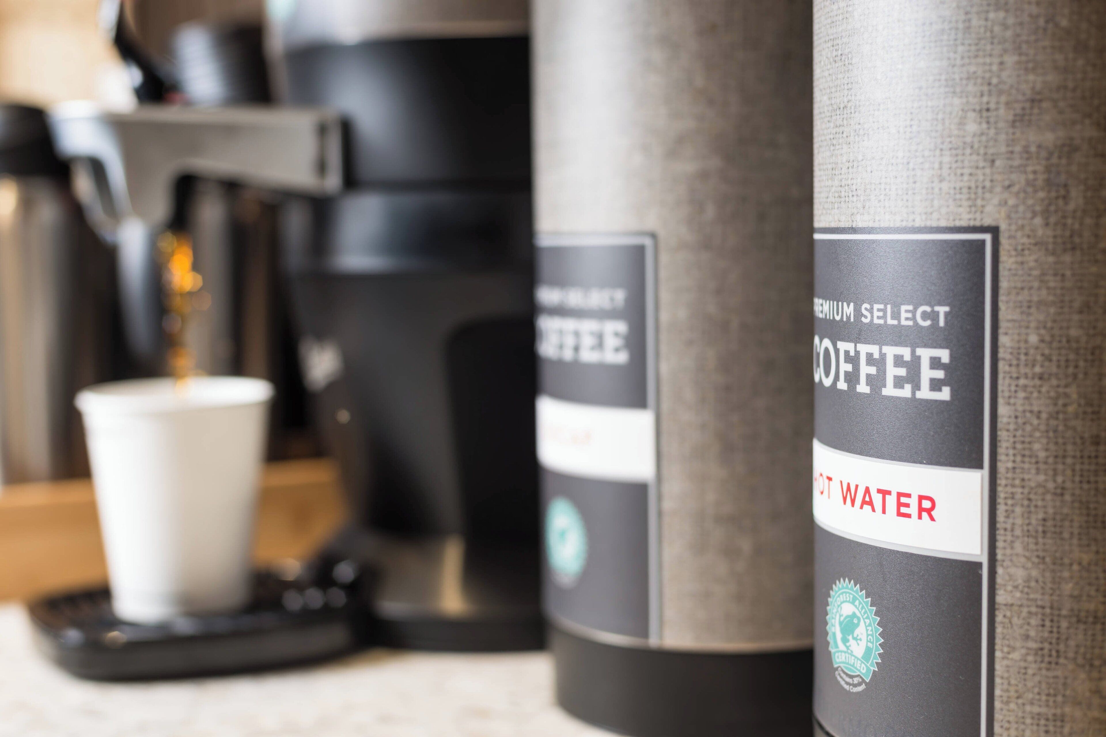 Una màquina de cafè i una capsula de cafè amb una etiqueta que indica aigua calenta.