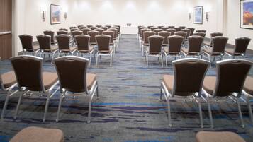A conference room with rows of chairs, a long table at the front, and a patterned carpet.