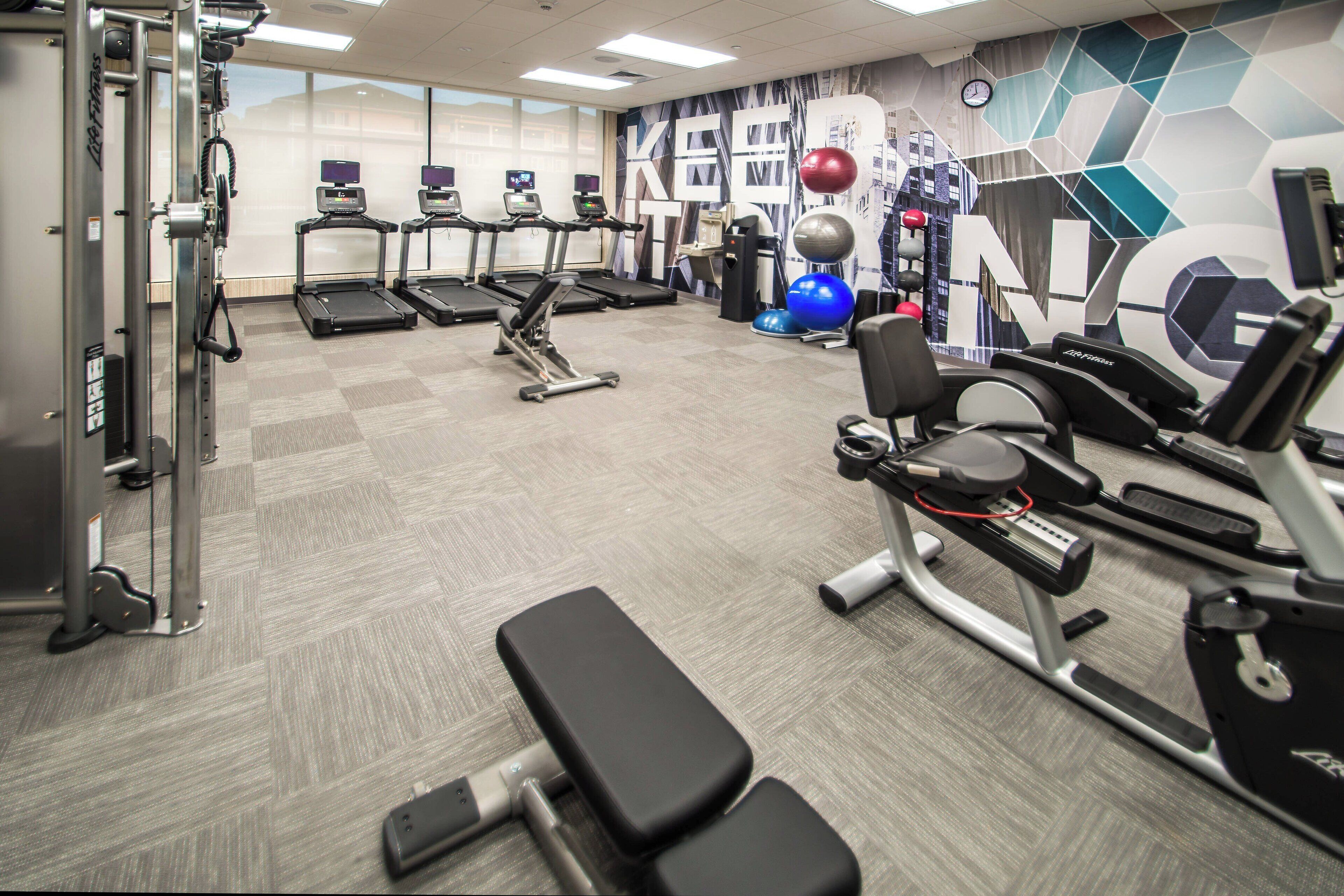 A gym with treadmills, weight machines, and exercise balls.