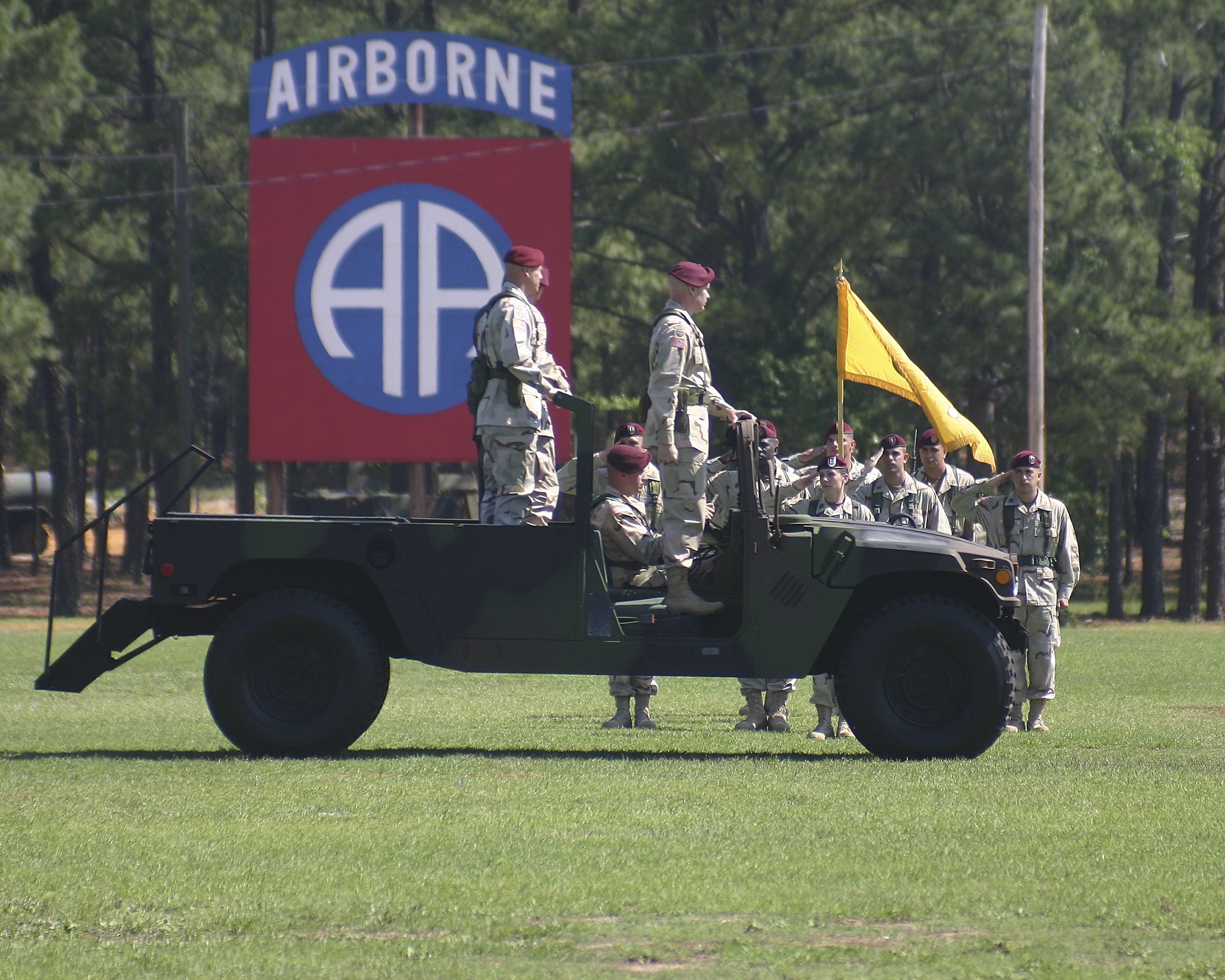 A military vehicle with soldiers standing on the back.