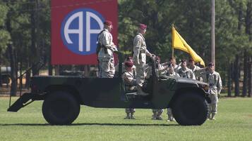 A military vehicle with soldiers standing on the back.