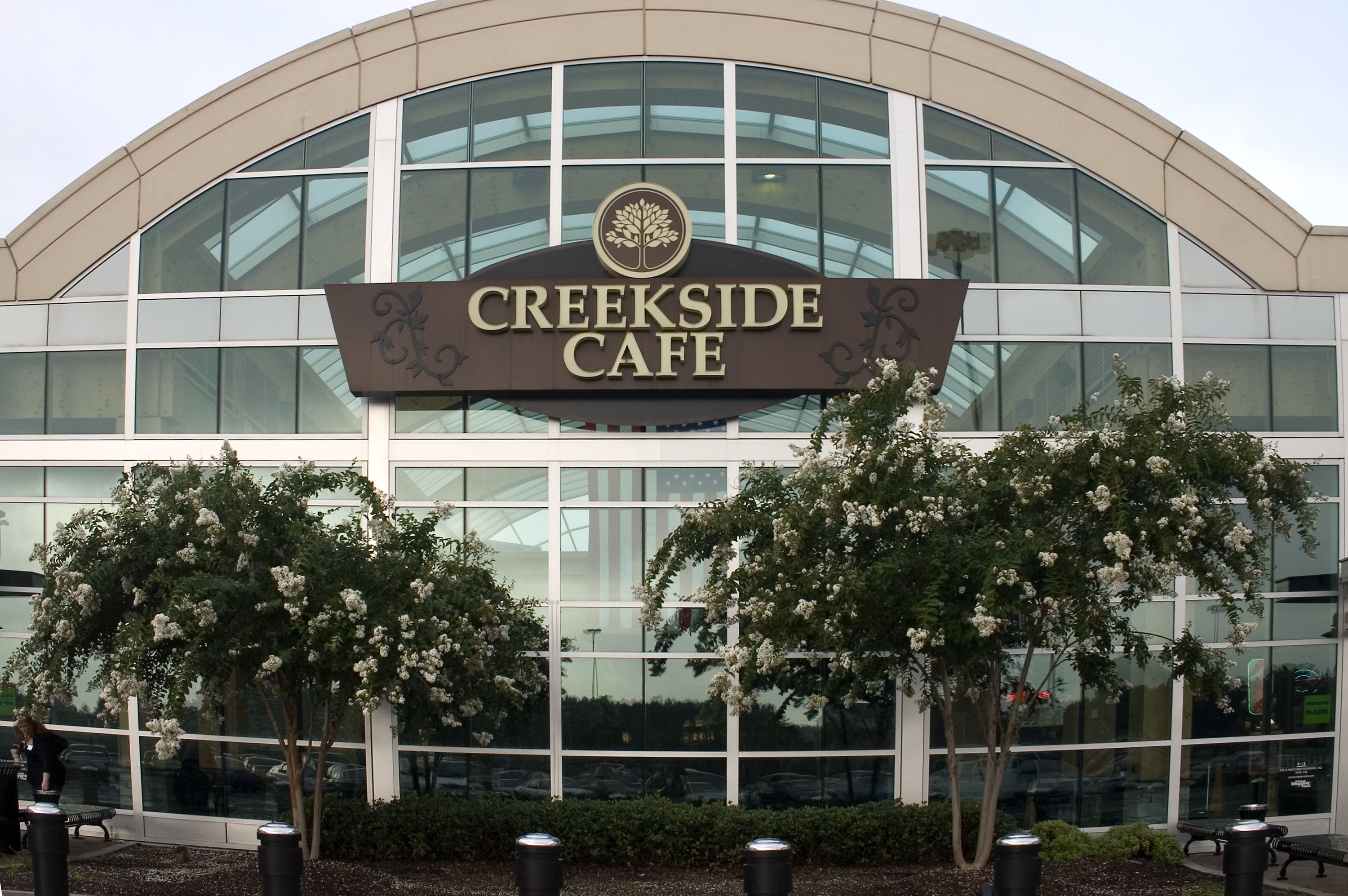 A building with a sign that reads "Creekside Cafe" and a large glass window facade.