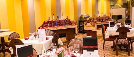 Un restaurante con mesas dispuestas para comer, una zona de bar y una escalera que sube a un nivel superior.
