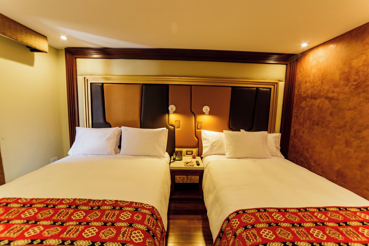 A hotel room with two beds, a nightstand with a telephone, and a mirror above the beds.