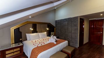 A hotel room with a large bed, a wooden bench, a marble bedside table, and a stone accent wall.