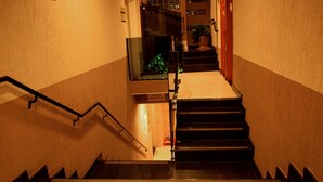 A staircase with a handrail, a sign indicating an emergency exit, and a potted plant at the top. - Hotel Pousada Estrela do Mar (Penha)