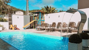 A swimming pool with a slide, lounge chairs, and a covered seating area. - Hotel Pousada Estrela do Mar (Penha)