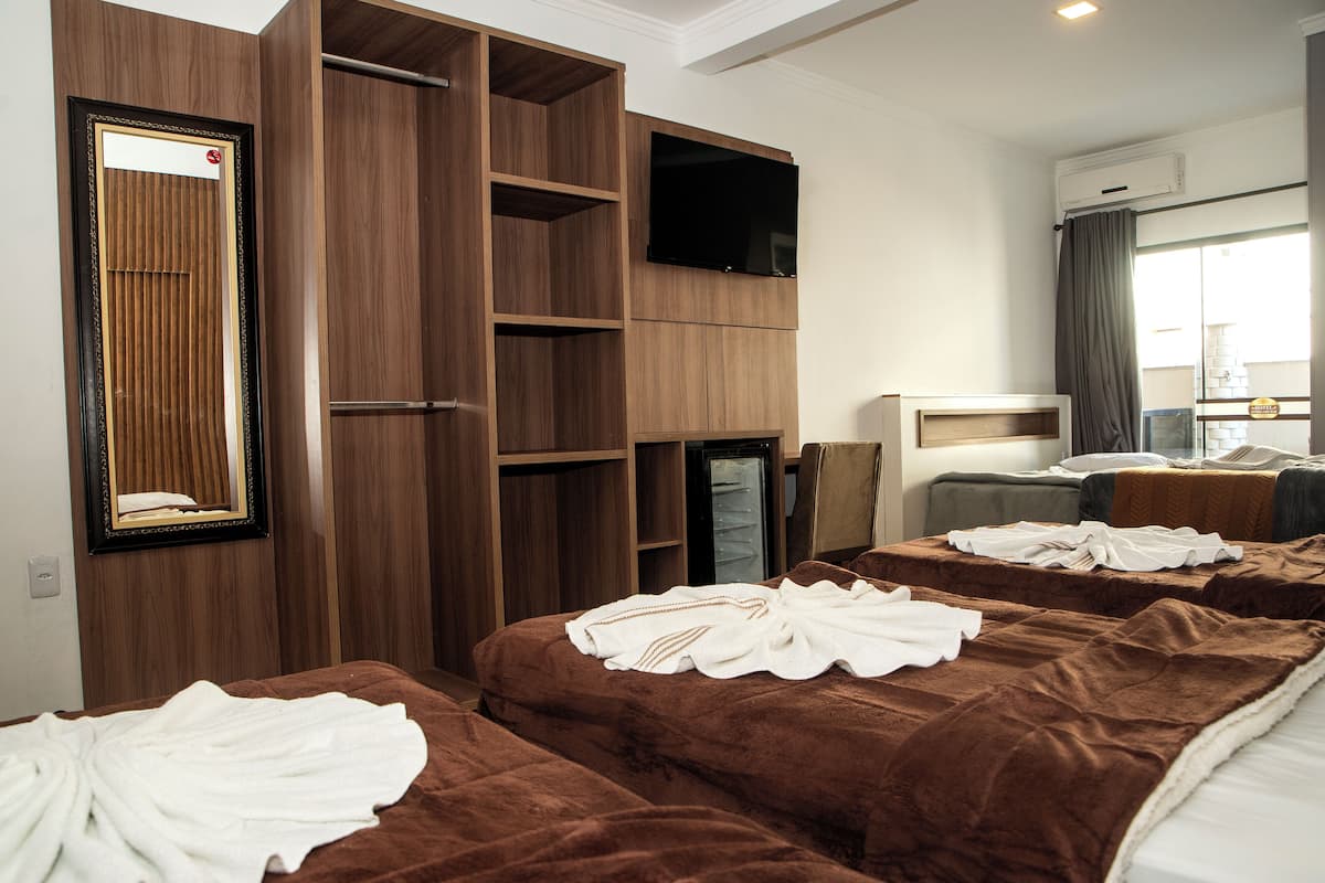 A hotel room with a large wardrobe, a flat-screen TV, and two beds with towels.