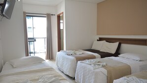 A hotel room with three beds, a TV, and a balcony with curtains. - Hotel Pousada Estrela do Mar (Penha)