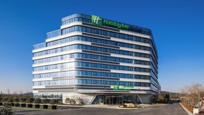 A multi-story Holiday Inn Express hotel with a modern design, featuring a prominent green logo and a clear sky in the background. - Holiday Inn Express Suzhou Taihu Lake by IHG (Suzhou)