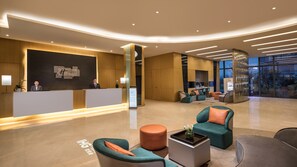 A hotel reception area with a modern design, including a reception desk, seating area with sofas, and a large window offering a view. - Holiday Inn Express Suzhou Taihu Lake by IHG (Suzhou)