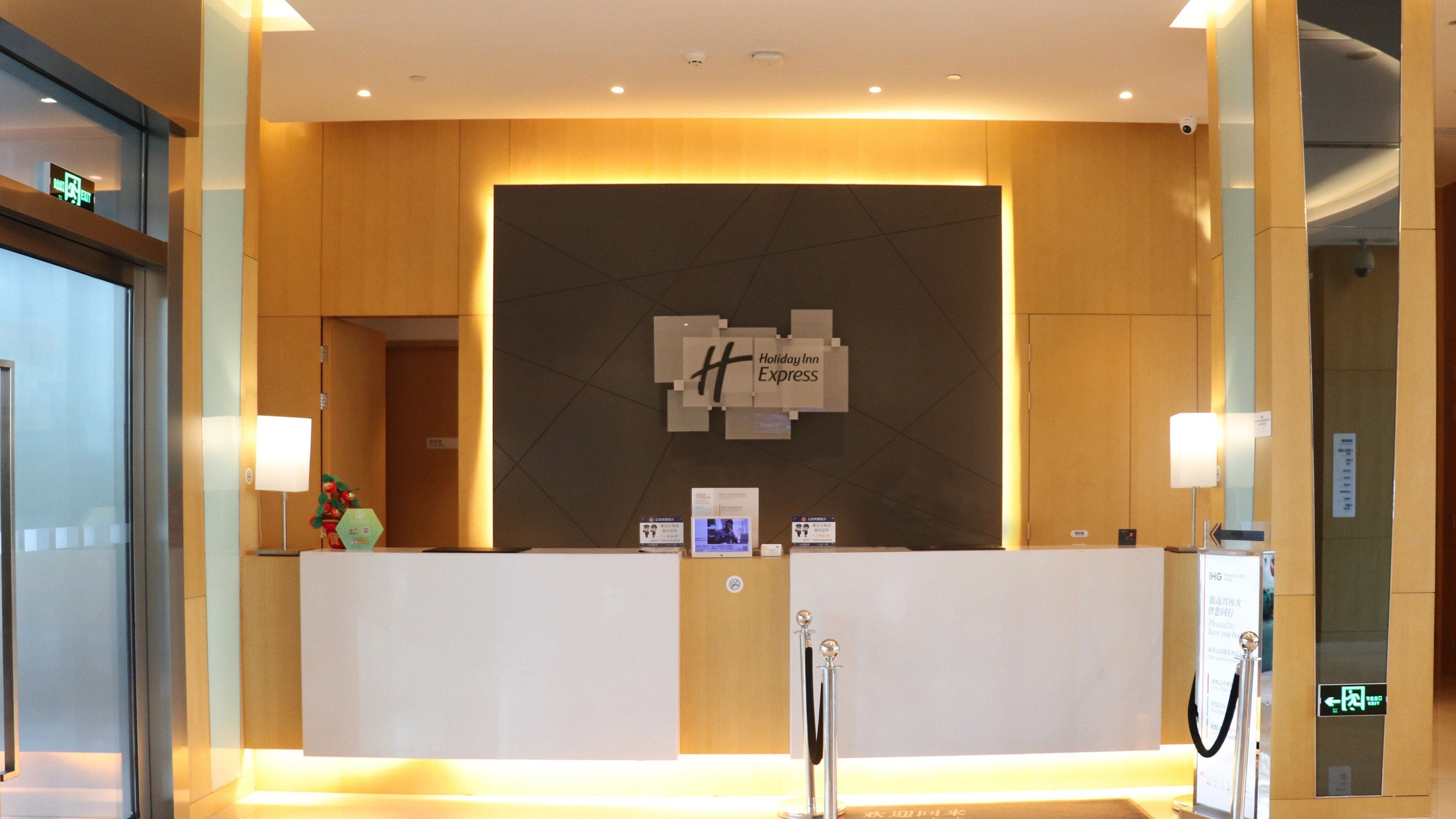 Una recepción con un cartel de Holiday Inn Express, una pantalla digital y una cámara de seguridad.