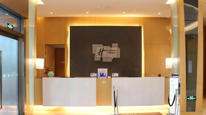 A reception desk with a Holiday Inn Express sign, a digital screen, and a security camera. - Holiday Inn Express Suzhou Taihu Lake by IHG (Suzhou)