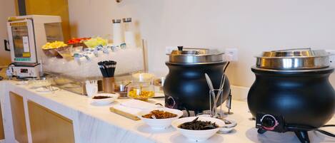 A buffet setup with various food containers and utensils.